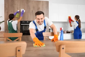 Male janitor cleaning table in kitchen