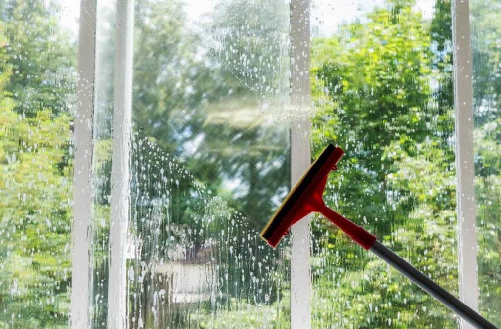 Cleaning windows using squeegee.