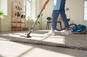 Woman cleaning carpet with vacuum cleaner in the living room at home.