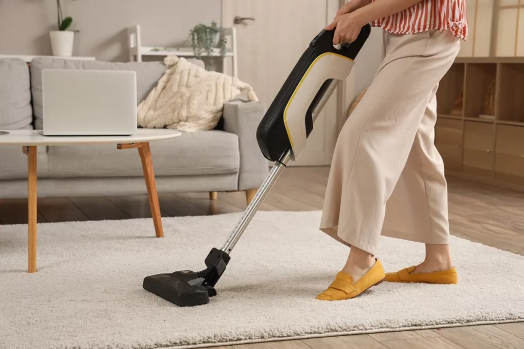 Woman cleaning carpet with vacuum cleaner in living room