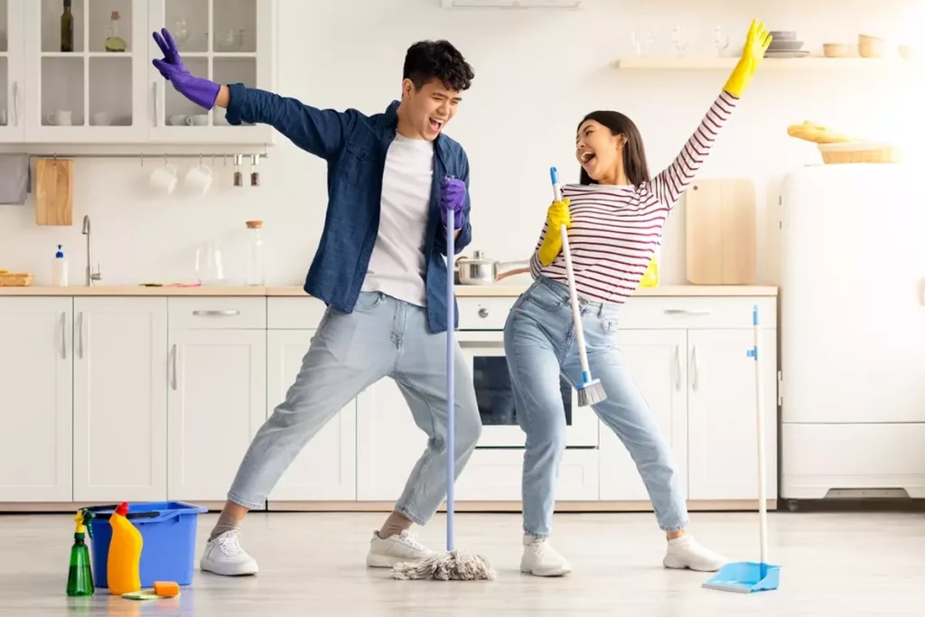 Couple cleaning kitchen using broom and mop while housekeeping